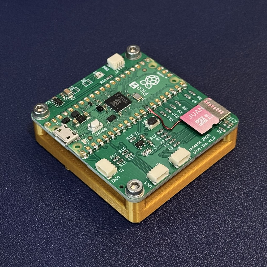 The assembled pico-llm board: a Raspberry Pi Pico 2 on a custom green PCB with a microSD card inserted, mounted on a gold 3D-printed base, with a red bodge wire running to the card slot